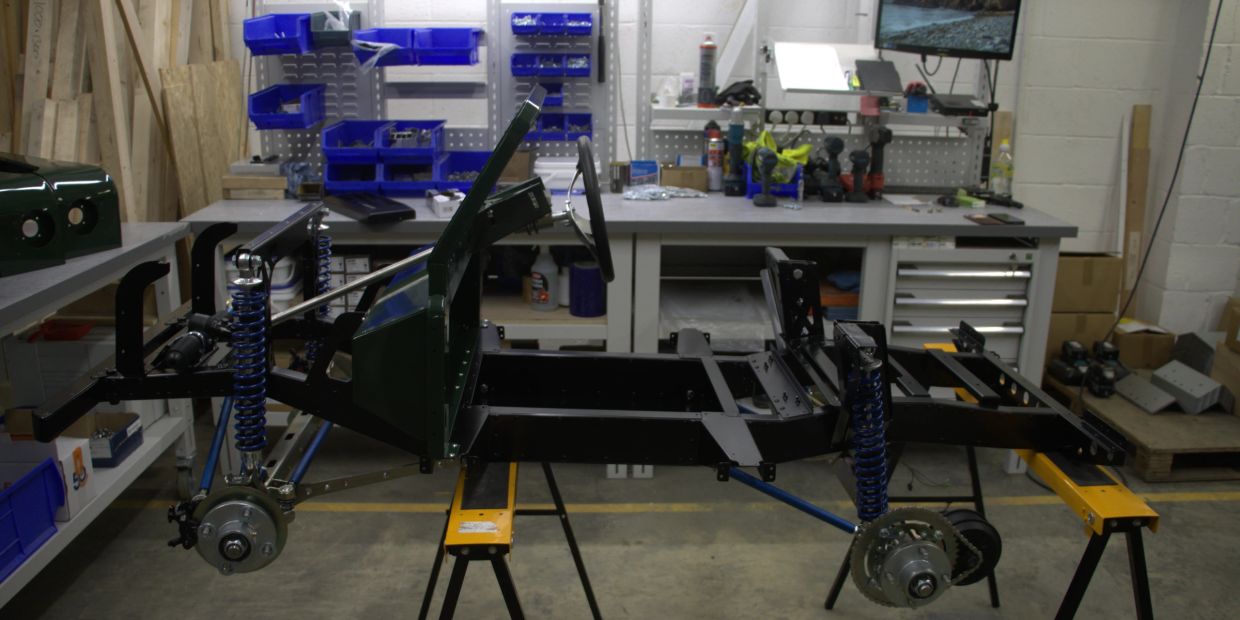 Partially assembled vehicle frame in workshop.