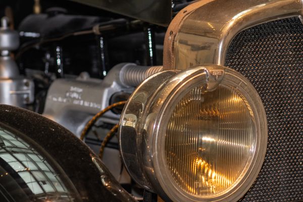 Close-up of a vintage car headlight and engine.