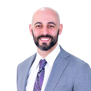 Smiling bald man in gray suit and purple tie.