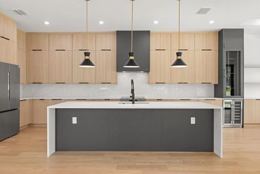 Modern kitchen with light wood cabinets and black accents.