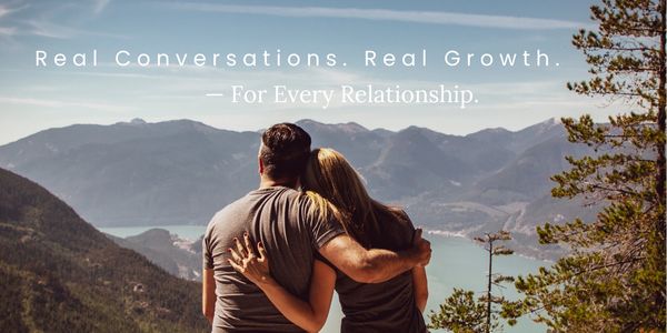 Partners connecting on a park bench with a sparkling blue bay and majestic mountain backdrop.