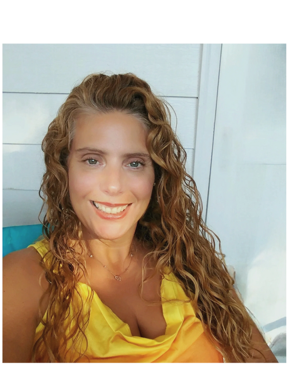 Smiling woman with curly hair in a yellow top.