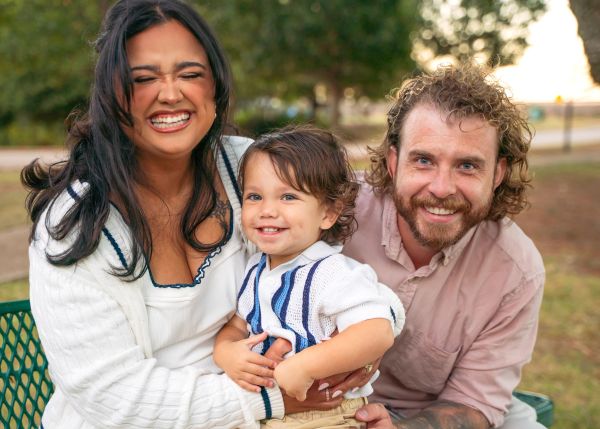 Happy family smiling outdoors, enjoying a joyful moment together.