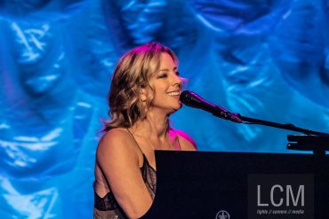 Woman singing and playing piano on stage.