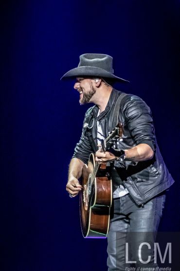 Musician in a cowboy hat playing guitar on stage.