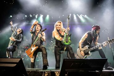Rock band performing energetically on stage with guitars.
