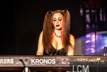 Woman playing a keyboard on stage with dramatic makeup.