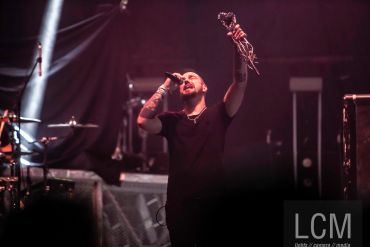 A male singer passionately performing on stage with a microphone in hand.