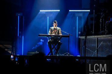 A musician performs solo on keyboard under dramatic blue stage lights.