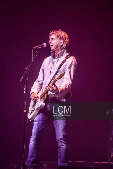 Musician performing live on stage with electric guitar.