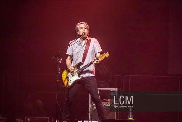 Musician playing guitar on stage during a concert.