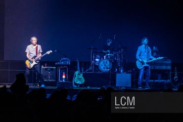 Band performing live on stage with blue lighting.
