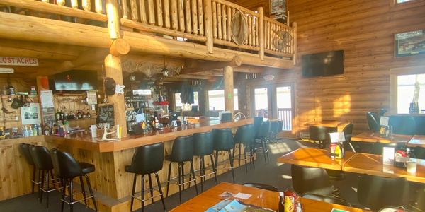 Cozy rustic bar and dining area with wooden interiors and sunlight streaming in.