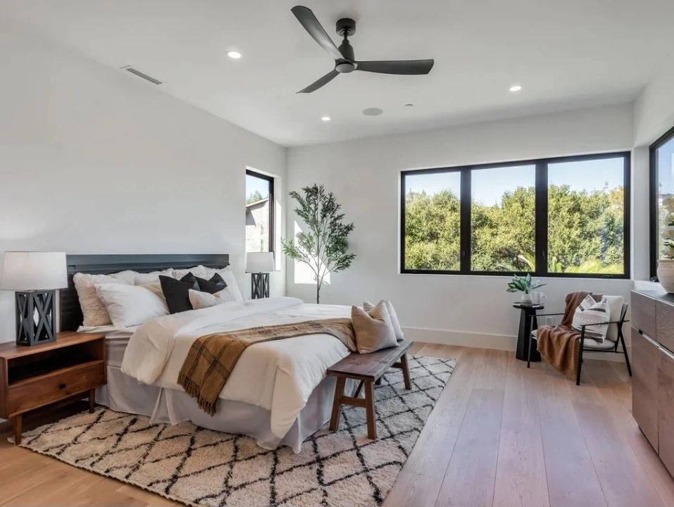 Bright, modern bedroom with large windows and cozy decor.