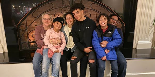 Family sitting together by the fireplace, smiling happily.
