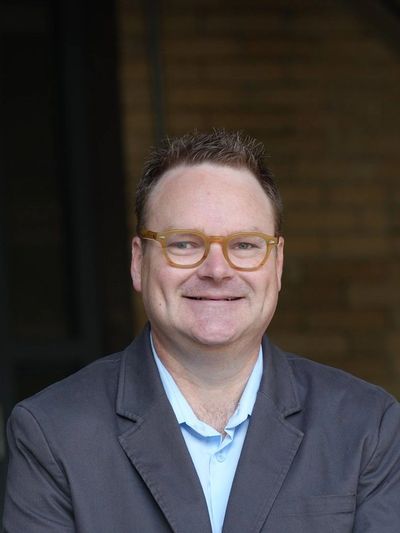 Smiling man in glasses and suit jacket.