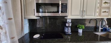 Modern kitchen countertop with coffee maker, stovetop, and microwave.