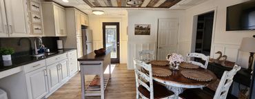 Cozy kitchen and dining area with rustic white furniture and natural wood accents.