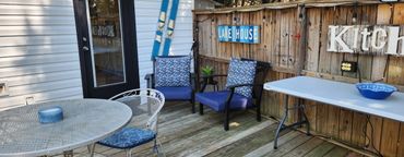 Cozy outdoor patio with blue cushioned chairs and a small table on a wooden deck.