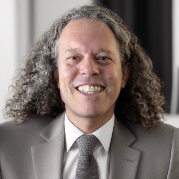 Smiling man with curly hair wearing a suit and tie.