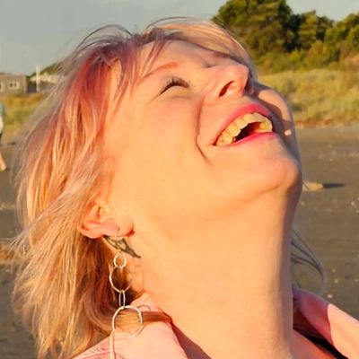 Woman laughing joyfully outdoors in sunlight.