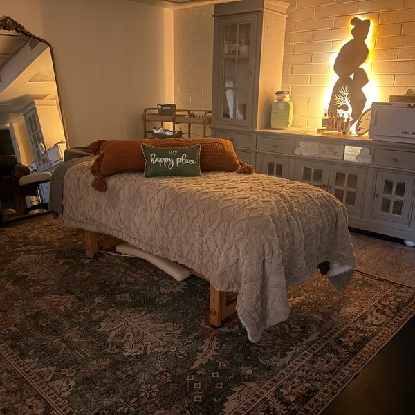 Cozy massage room with warm lighting and a decorative pillow.