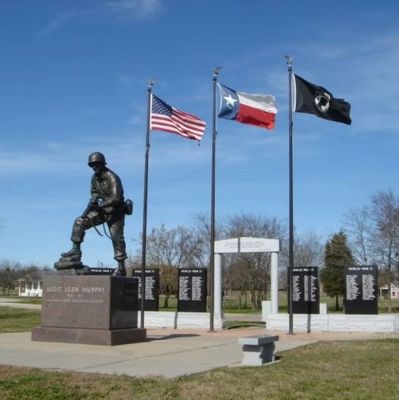 A soldier statue with American, Texas, and POW flags flying.