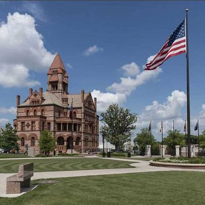 Historic brick courthouse with American flags on a sunny day.