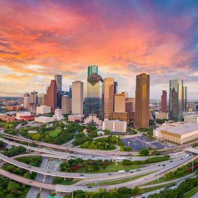 Vibrant sunset over a bustling city skyline with highways in foreground.