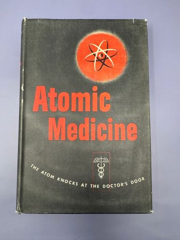 Vintage book titled Atomic Medicine with an atom symbol and medical caduceus on cover.