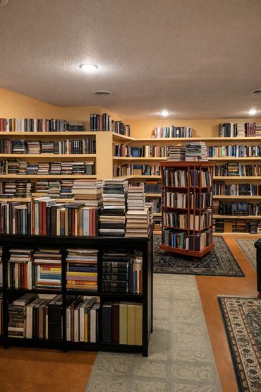 Cozy room filled with numerous books on shelves and tables.