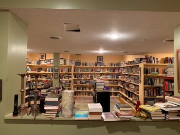 A cozy room filled with numerous bookshelves and stacks of books.