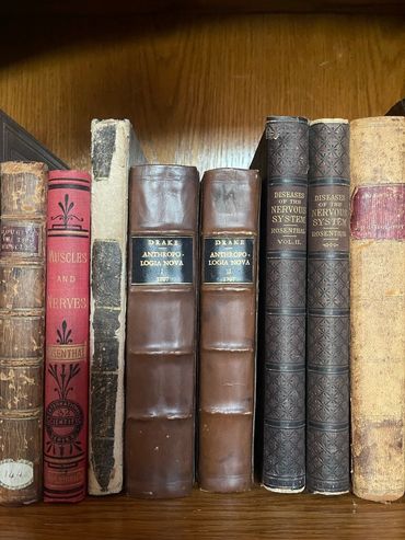 A collection of vintage medical books on a wooden shelf.