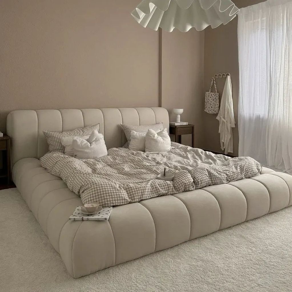 Modern beige bedroom with a cozy bed and natural light.