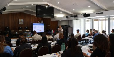 A training session designed filled with people listening to the speaker presenting.