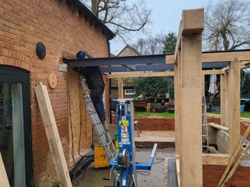 Person working on a wooden structure attached to a brick house.