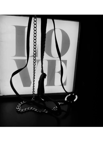 Chains and straps silhouetted against a glowing LOVE sign in black and white.