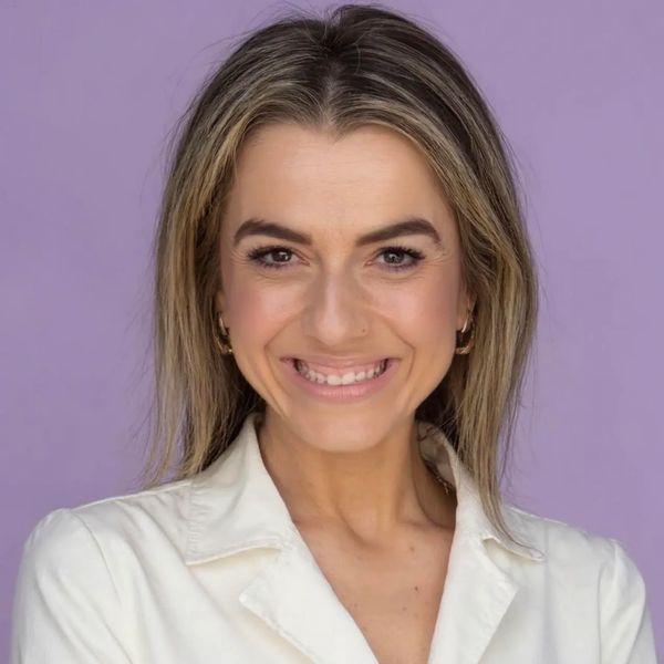 Smiling woman with blonde hair against a purple background.
