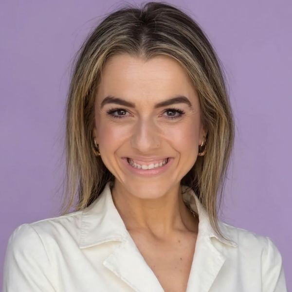Smiling woman with blonde hair against a purple background.
