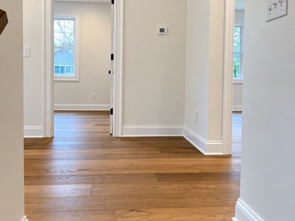 Empty hallway with wooden flooring and white walls.
