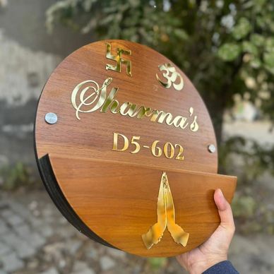 Wooden nameplate with 'Sharma's D5-602' and religious symbols.