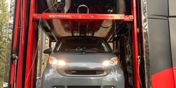 Smart car parked inside HDToy Box lower level with 2 motorcycles loaded onto raised platform