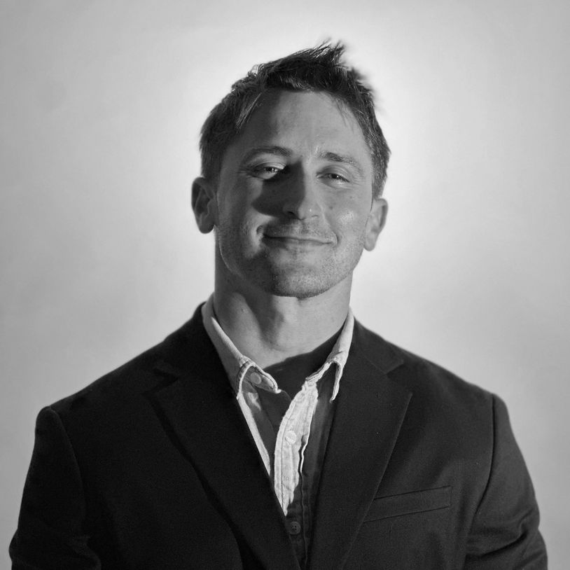 Man smiling confidently in black suit.