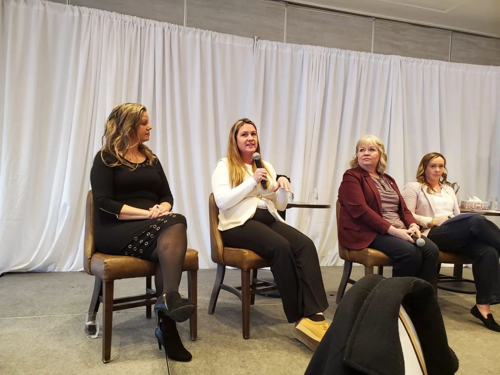 Four women seated on chairs participate in a panel discussion.