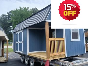 Blue tiny house on wheels with a small porch and wooden railing.
