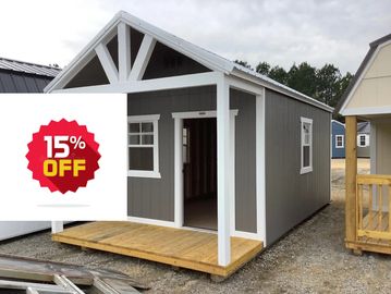 Small gray and white wooden shed with a front porch under a cloudy sky.