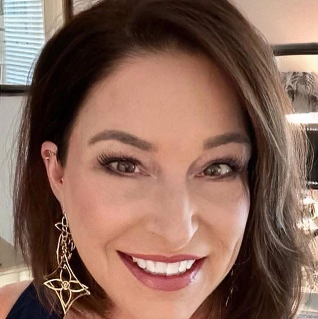 Close-up portrait of a smiling woman with elegant earrings and makeup.