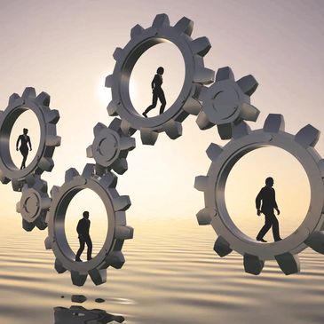 Silhouettes of people walking inside interconnected gears over water.