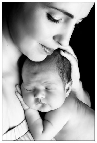 Mother tenderly holding her sleeping baby.
