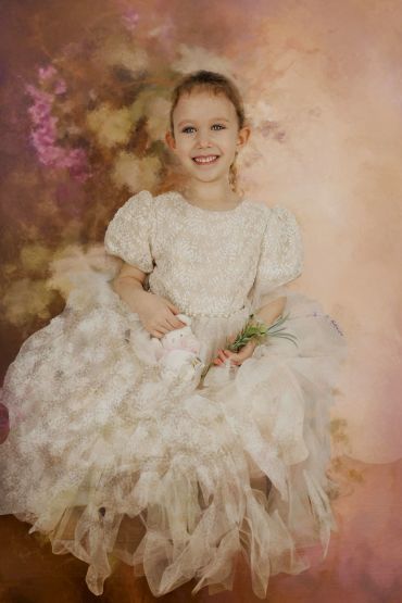 Young girl in a white lace dress smiling.